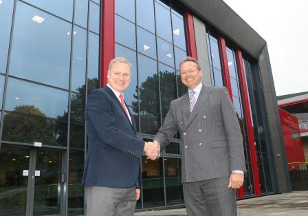 Representatives from university and college shake hands to mark new partnership