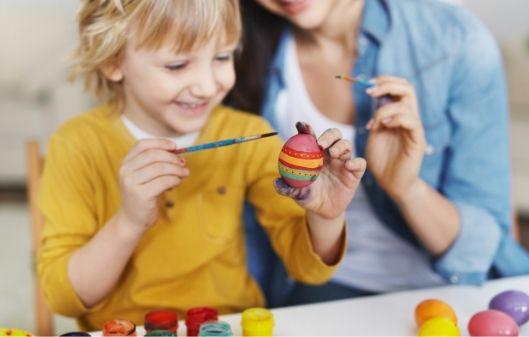 Young child enjoying painting an Easter egg.