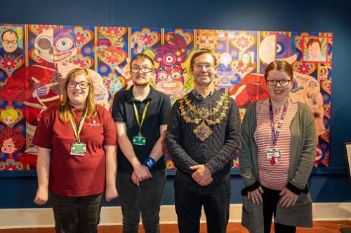 Photo of Mayor Andy Abrahams with Abby Storer, Harry Wynn and Ellie Overton in front of a colourful picture at the exhibition