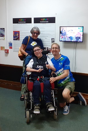 A photo of Kieron Norton in a wheelchair with his parents Sharon and Andrew Norton crouching behind him