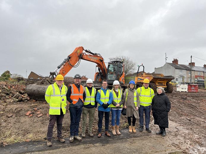 MDC and Mercer reps standing in the mud with a large orange digger behind them