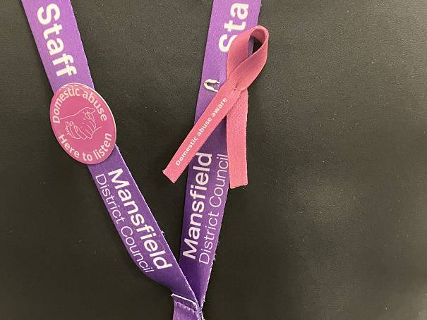 Photo of council staff lanyard with a Domestic Abuse Aware ribbon and badge