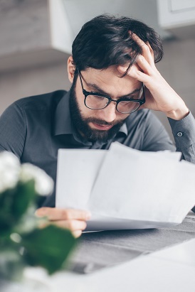 Image of worried man looking at bills