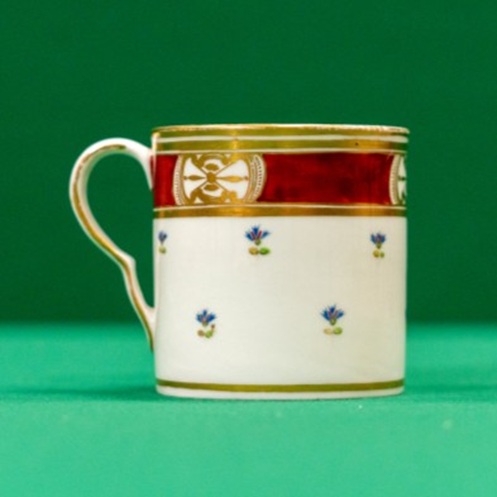 Small coffee cup with red and gilt border, and tiny blue flowers