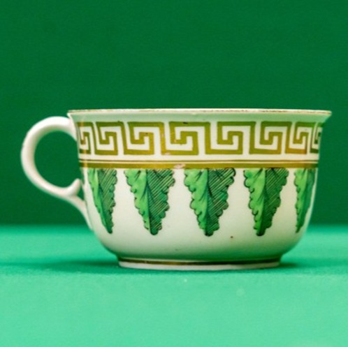 Broad teacup with gilt geometric border and green leaves
