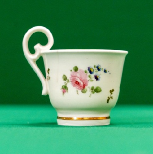 Delicate coffee can with curly handle and decoration of roses