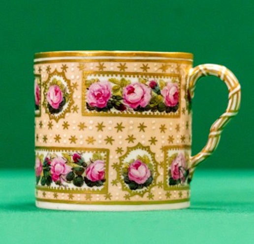 Small coffee cup with salmon pink and gilt background, and panels of roses