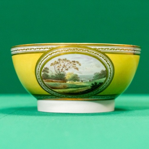 A low ceramic bowl decorated with landscapes