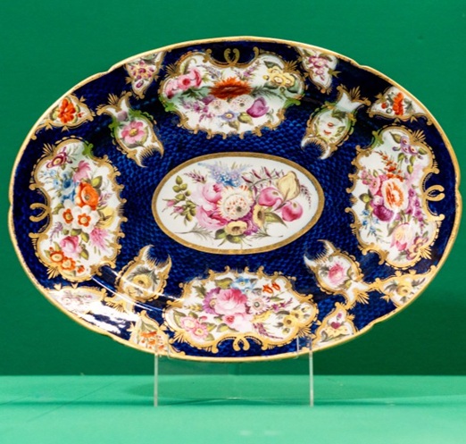 Large oval platter, decorated with panels of roses, on a dark blue background