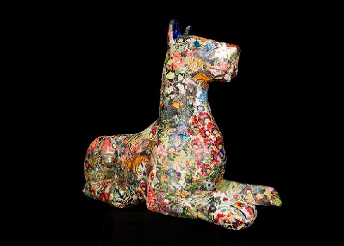 A statue of an alsation-type dog decorated all over with colourful decoupage