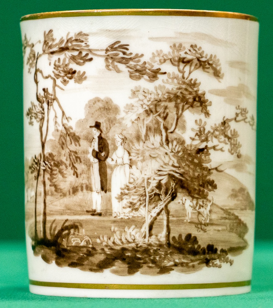 A porcelain cup with a man and woman walking in a wood