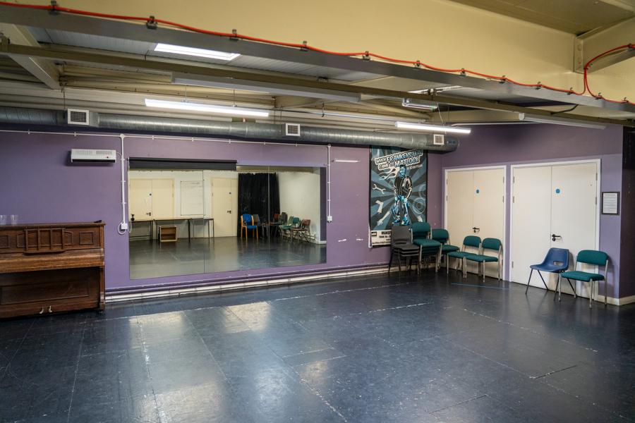 a room with dark floor and mirrors on walls used for theatre rehearsals