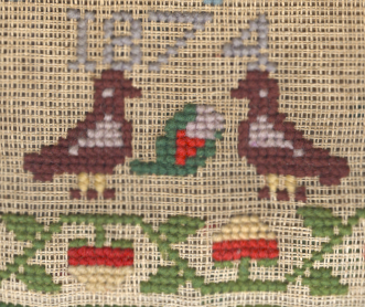 A detail from a cross-stitch sampler, showing birds and flowers