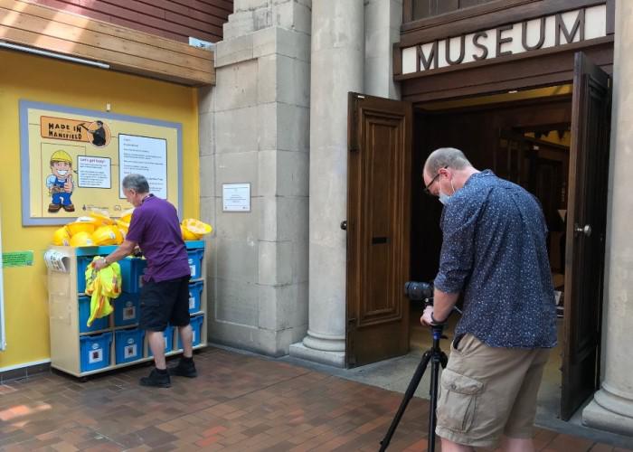 Two people setting up and photographing an exhibition