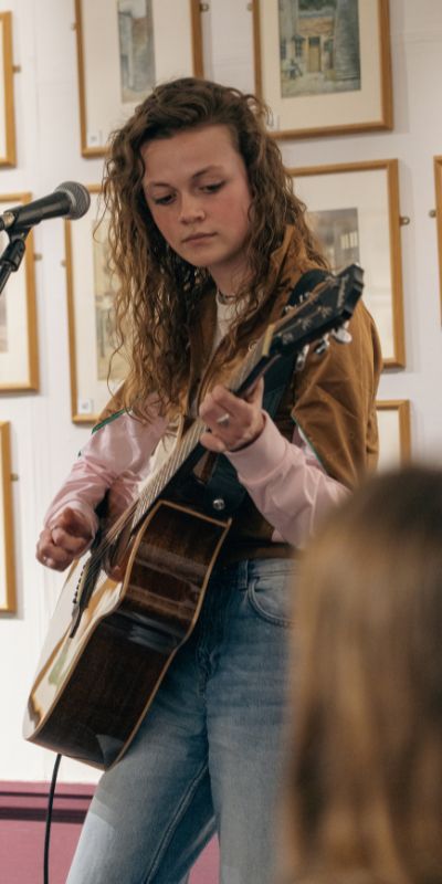 This image shows a young person playing a acoustic guitar